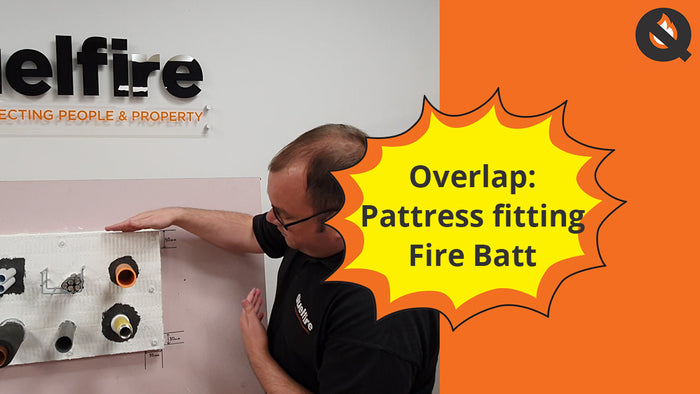 Alec Purdie, Technical, pointing to a Quelfire demo board. Half of the screen is orange, titled 'Overlap: pattress fitting fire batt'. The Quelfire logo can be found in the right-hand corner.
