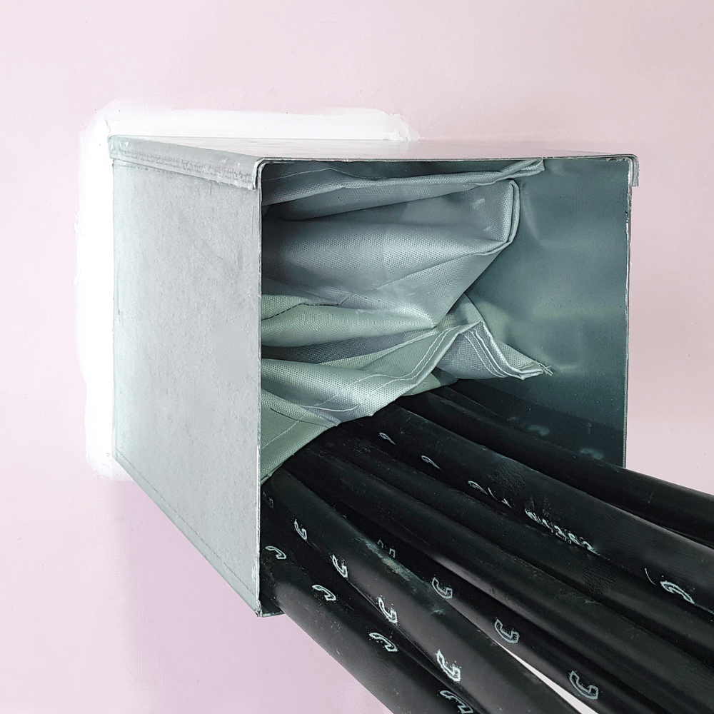 Metal trunking with black electrical cables emerging from the box, firestopped with Quelfire pillows.