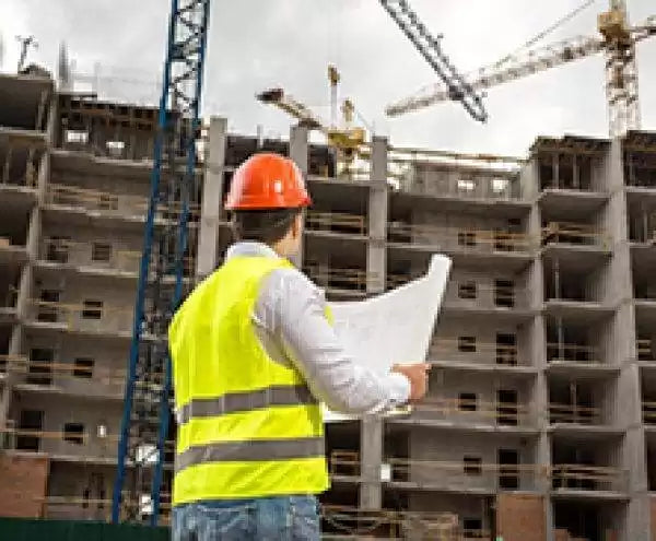 A construction worker wearing a hard hat and high-vis vest on site.