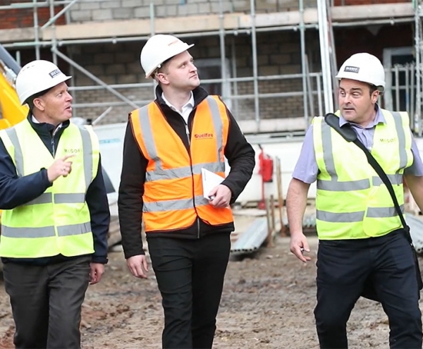 Three men in hi-vis being shown round a construction site